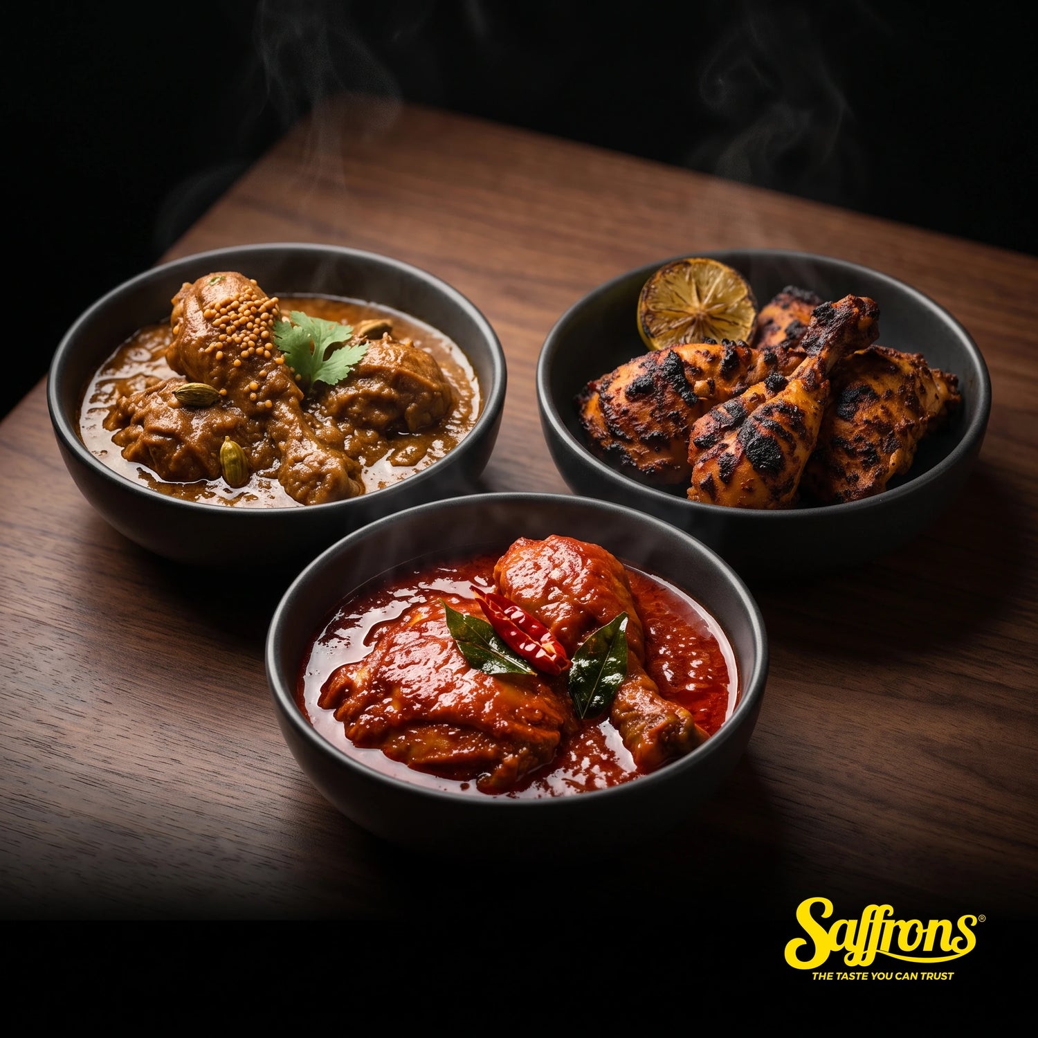 Three dark ceramic bowls side by side holding chicken masak merah in scarlet gravy, chicken masala in brown gravy and charred tandoori chicken